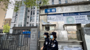 Police officers patrol past a barricaded building following a fire at a hospital in Beijing, Wednesday, April 19, 2023. (AP Photo/Andy Wong) 