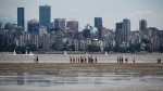 People walk on tidal flats off Jericho Beach during low tide in Vancouver, B.C., Sunday, July 19, 2020. THE CANADIAN PRESS/Darryl Dyck