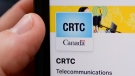 A person navigates to the online social media pages of the CRTC on a cellphone in Ottawa on Monday, May 17, 2021. THE CANADIAN PRESS/Sean Kilpatrick