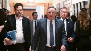 Premier Francois Legault, center, walks to the site of a press conference, March 13, 2024. Media relations director Manuel Dionne is at his left side. THE CANADIAN PRESS/Jacques Boissinot

