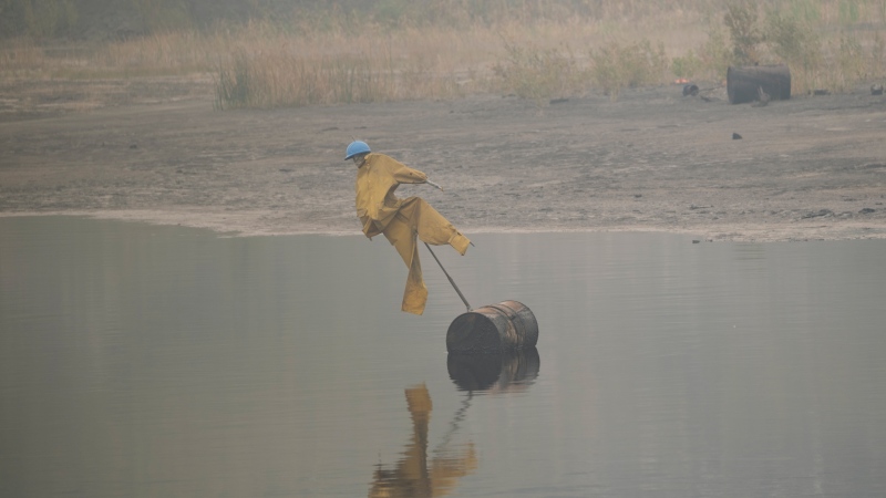 A scarecrow floats on the surface of a tailings pond to keep birds from landing in the toxic wastewater from oil production near Fort McMurray, Canada, on Saturday, Sep. 2, 2023. (AP Photo/Victor R. Caivano)