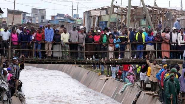 People stand on a bridge, as they watch houses in riparian land being demolished in the Mukuru area of Nairobi, Tuesday, May. 7, 2024. (AP Photo/Brian Inganga)