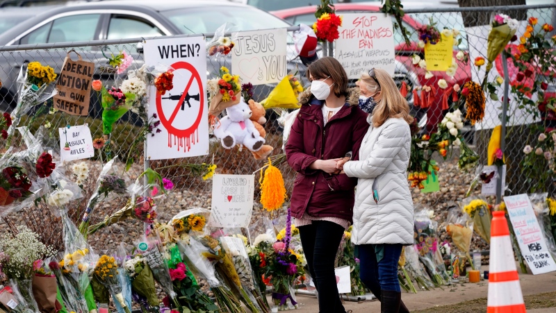 Mourners walk along the temporary fence put up around the parking lot of a King Soopers grocery store where a mass shooting took place earlier in the week, Thursday, March 25, 2021, in Boulder, Colo. (AP Photo/David Zalubowski, File)