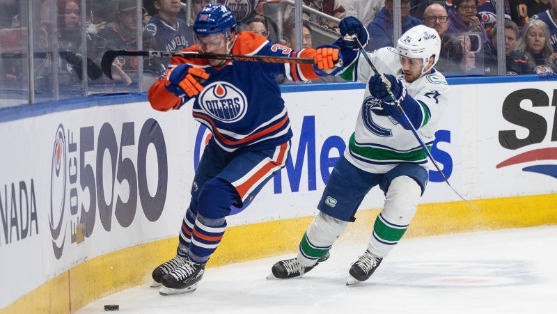Vancouver Canucks' Pius Suter (24) and Edmonton Oilers' Sam Carrick (39) battle for the puck during second period NHL action in Edmonton, Saturday, April 13, 2024. (Jason Franson / The Canadian Press) 