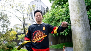 Vancouver Mayor Ken Sim poses wearing a Canucks jersey after raising the team's flag at city hall. (Vancouver Canucks/X)
