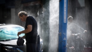 A man cools off at a temporary misting station during a heat wave in Vancouver on Aug. 16, 2023. (Darryl Dyck / The Canadian Press) 