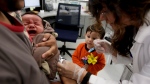 In this Dec. 10, 2014, file photo, Julietta Losoyo, right, a registered nurse at the San Diego Public Health Center gives Derek Lucero a whooping cough injection while in his fathers Leonel's arms as his brother Iker, 2, looks on in San Diego. (AP Photo/Chris Carlson, File) 