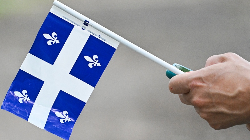 A person holds a Quebec flag during Saint-Jean-Baptiste Day in Montreal, Saturday, June 24, 2023. (Graham Hughes/The Canadian Press)