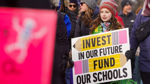 A child holds a sign while walking in front of Saskatchewan Legislative Building during a one-day, province-wide strike organized by Saskatchewan Teachers' Federation before the 2024-2025 Saskatchewan budget is presented in Regina, on Wednesday, March 20, 2024. THE CANADIAN PRESS/Heywood Yu