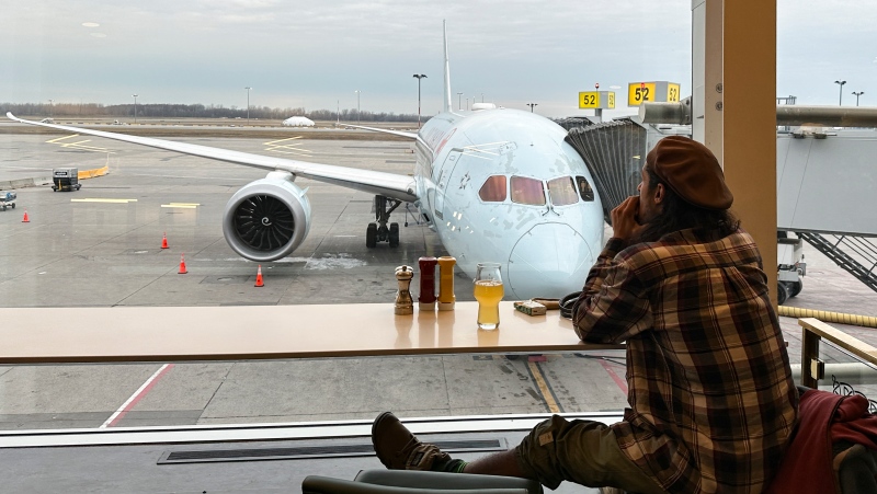 A traveller looks at an Air Canada plane as he waits for his flight at Pierre Elliott Trudeau International Airport in Montreal, Dec. 23, 2023 (Christinne Muschi / THE CANADIAN PRESS)