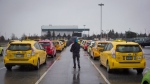 A taxi driver walks past cabs while waiting for passengers at Vancouver International Airport, in Richmond, B.C., on Tuesday March 7, 2017. THE CANADIAN PRESS/Darryl Dyck