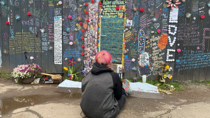 A person sits in front of the mural dedicated to homeless people in Moncton. (Source: Derek Haggett/CTV News Atlantic)