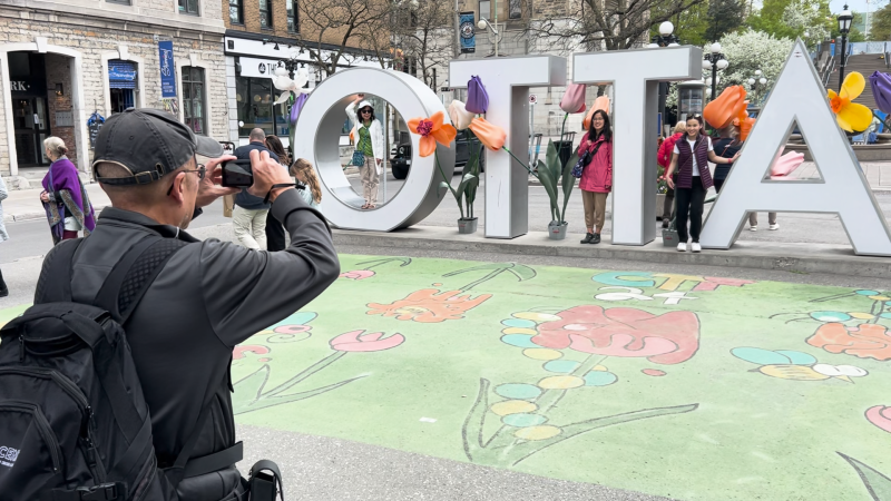 A family poses for a photo at the ByWard Market Ottawa sign on May 12, 2024 (Sam Houpt/CTV News)