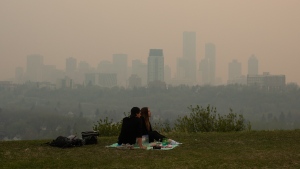 Smoke from wildfires blankets the city as a couple has a picnic in Edmonton on Saturday May 11, 2024. (Jason Franson/The Canadian Press)