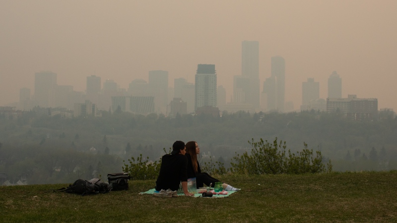 Smoke from wildfires blankets Edmonton as a couple has a picnic on Saturday, May 11, 2024. (Jason Franson / The Canadian Press) 