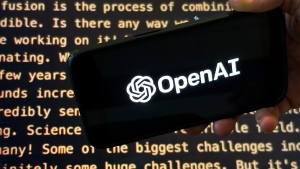 The OpenAI logo appears on a mobile phone in front of a screen showing a portion of the company website, Tuesday, Nov. 21, 2023, in New York. (Peter Morgan / The Associated Press, File)