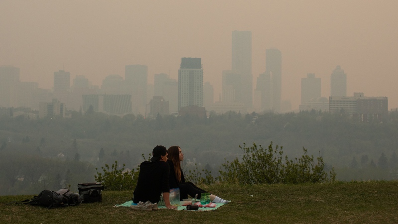 Smoke from wildfires blankets the city as a couple has a picnic in Edmonton Alberta, on Saturday May 11, 2024. THE CANADIAN PRESS/Jason Franson