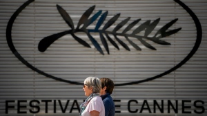 Two people walk past the Cannes film festival logo during preparations for the 77th international film festival, Cannes, southern France, Monday, May 13, 2024. The Cannes film festival runs from May 14 until May 25, 2024. (AP Photo/Andreea Alexandru)