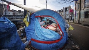 FILE - Two men share a meal in a makeshift tent camp outside the Petit Chateau reception center in Brussels, Tuesday, Jan. 17, 2023. (Olivier Matthys / The Associated Press)