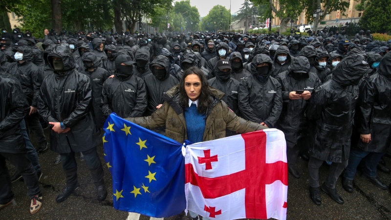 A woman holds a Georgian national and an EU flags near the Parliament building in the centre of Tbilisi, Georgia, Tuesday, May 14, 2024. (Zurab Tsertsvadze / AP Photo)