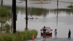 People stand at the edge of floodwater as vehicles are seen abandoned in water following a major rain event in Halifax on Saturday, July 22, 2023. A long procession of intense thunderstorms have dumped record amounts of rain across a wide swath of Nova Scotia, causing flash flooding, road washouts and power outages. (Source: THE CANADIAN PRESS/Darren Calabrese)
