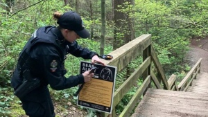 This photo posted to social media on May 14, 2024 shows a conservation officer installing a sign warning people about bears on a trial. (Image credit: Facebook/Conservation Officer Service) 
