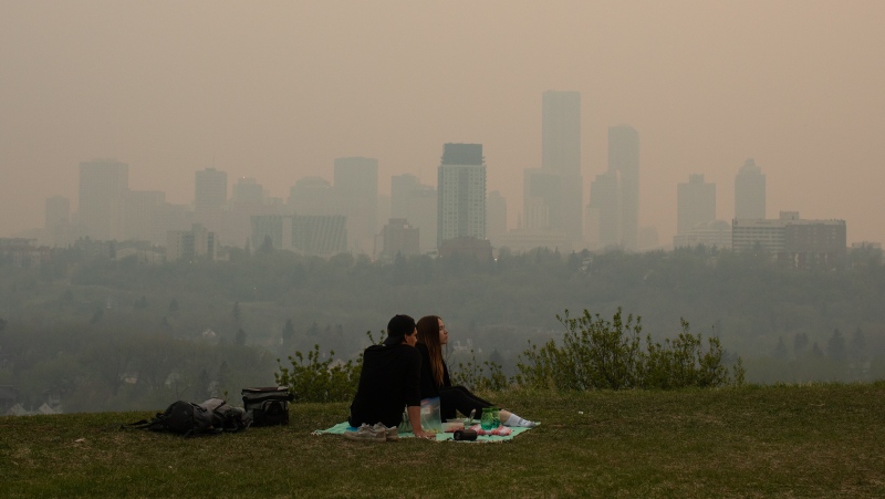 Smoke from wildfires blankets the city as a couple has a picnic in Edmonton Alberta, on Saturday May 11, 2024. THE CANADIAN PRESS/Jason Franson