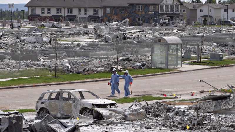 Workers put out markers around a devastated area of Timberlea in Fort McMurray Alta, on Thursday, June 2, 2016. (Jason Franson / The Canadian Press)
