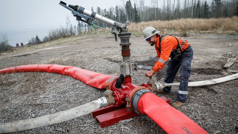 Justin Massie, wildfire specialist with Fire and Flood Emergency Service Ltd., adjusts a valve on a wildfire suppression water cannon southeast of Fort McMurray, Wednesday, May 15, 2024.THE CANADIAN PRESS/Jeff McIntosh