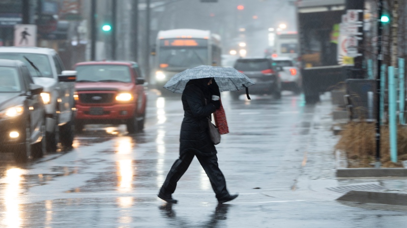 A pedestrian shields themselves from rain and wind during a rainfall warning in Halifax on Thursday, January 26, 2023. THE CANADIAN PRESS/Darren Calabrese 