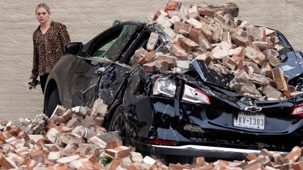 A woman looks at the damage caused by fallen bricks from a building wall in the aftermath of a severe thunderstorm, Friday, May 17, 2024, in Houston. (AP Photo/David J. Phillip)
