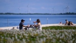 Allison Quan, left, and Jana Szpala enjoy the warm weather at Breakwater Park on the shores of Lake Ontario in Kingston, Ont., on Thursday, May 16, 2024. (Justin Tang/THE CANADIAN PRESS)