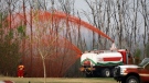 A pumper truck sprays fire retardant on trees around the evacuated neighbourhood of Beacon Hill in Fort McMurray, Alta., on Wednesday, May 15, 2024. (Jeff McIntosh / The Canadian Press)