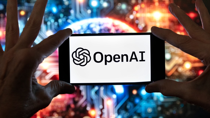 The OpenAI logo is seen displayed on a cell phone in front of an image on a computer screen generated by ChatGPT's Dall-E text-to-image model, Friday, Dec. 8, 2023, in Boston. (AP Photo/Michael Dwyer)