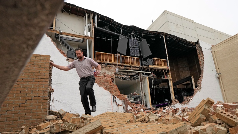 A man walks over fallen bricks from a damaged building in the aftermath of a severe thunderstorm Friday, May 17, 2024, in Houston.  (AP Photo/David J. Phillip)