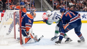 Vancouver Canucks' Nils Hoglander (21) scores on Edmonton Oilers goalie Stuart Skinner (74) as Ryan McLeod (71) defends during first period second-round NHL playoff action in Edmonton on Saturday May 18, 2024.THE CANADIAN PRESS/Jason Franson