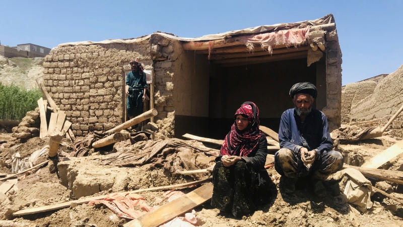 An Afghan couple sit near to their damaged home after heavy flooding in Ghor province in western Afghanistan Saturday, May 18, 2024. (AP Photo/Omid Haqjoo)