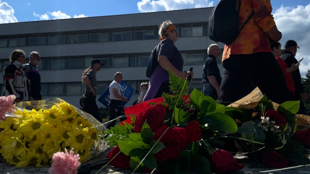 People gather and bring flowers outside the F. D. Roosevelt University Hospital, where Slovak Prime Minister Robert Fico, who was shot and injured, is being treated, in Banska Bystrica, central Slovakia, Sunday, May 19, 2024. (AP Photo/Lefteris Pitarakis)