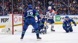 Edmonton Oilers winger Zach Hyman scores on Vancouver Canucks goalie Arturs Silovs as Pius Suter (24) and Quinn Hughes (43) look on during their second-round NHL playoff series on May 20, 2024, in Vancouver. (Darryl Dyck/The Canadian Press)
