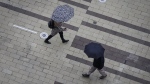 Pedestrians carry umbrellas as light rain falls in Surrey, B.C., on Friday, October 21, 2022. THE CANADIAN PRESS/Darryl Dyck