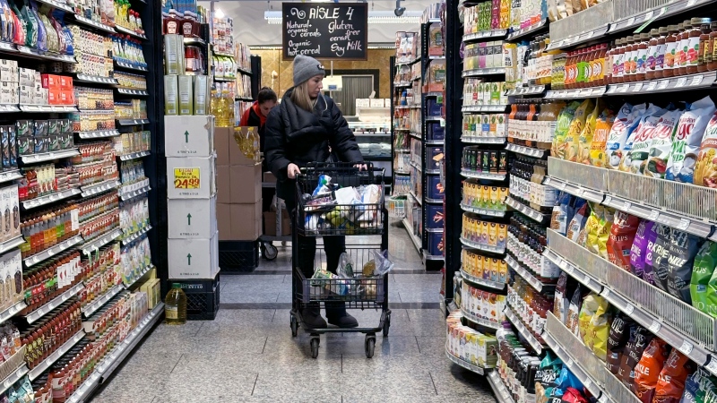 A woman checks prices as she shops at a grocery store on Friday, Jan. 19, 2024. (AP Photo/Nam Y. Huh)