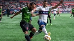 Cavalry FC's Sergio Camargo, left, and Vancouver Whitecaps' Luís Martins, right, compete for ball possession during the first half of a Canadian Championship quarterfinal soccer match, in Vancouver, on Tuesday, May 21, 2024. THE CANADIAN PRESS/Ethan Cairns