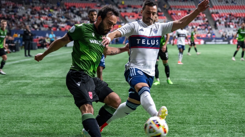Cavalry FC's Sergio Camargo, left, and Vancouver Whitecaps' Luís Martins, right, compete for ball possession during the first half of a Canadian Championship quarterfinal soccer match, in Vancouver, on Tuesday, May 21, 2024. THE CANADIAN PRESS/Ethan Cairns