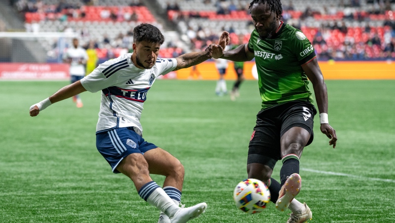 Vancouver Whitecaps' Ryan Raposo, left, is blocked by Cavalry FC's Bradley Kamdem Fewo, right, during the second half of a Canadian Championship quarterfinal soccer match, in Vancouver, on Tuesday, May 21, 2024. THE CANADIAN PRESS/Ethan Cairns