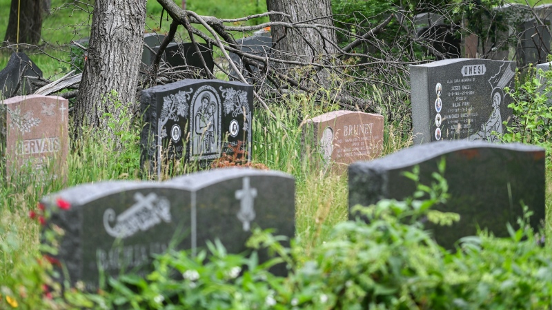 Overgrown foliage and fallen branches surround gravestones at Notre-Dame-des-Neiges Cemetery in Montreal, Sunday, July 9, 2023. (THE CANADIAN PRESS/Graham Hughes)