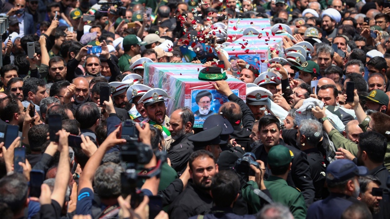 Mourners surround the flag-draped coffins of the late Iranian president Ebrahim Raisi and his companions during their funeral ceremony in  Mashhad, Iran, on Thursday, May 23, 2024.  (Iranian Presidency Office via AP)