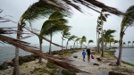Bob Givehchi, right, and his son Daniel, 8, Toronto residents visiting Miami for the first time, walk past debris and palm trees blowing in gusty winds, at Matheson Hammock Park in Coral Gables, Fla., Dec. 15, 2023. (AP Photo/Rebecca Blackwell)