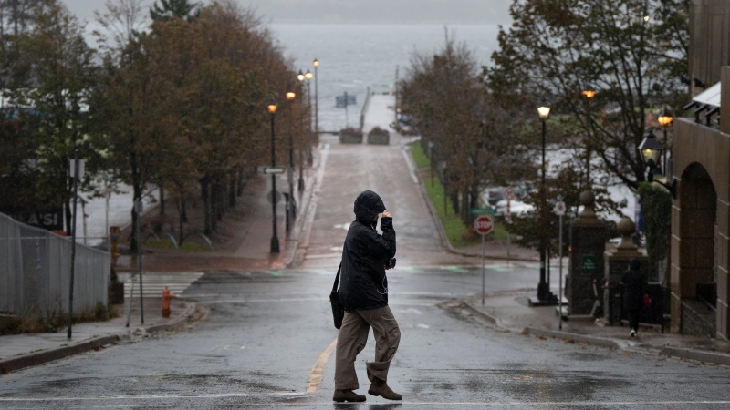 A pedestrian shields themselves from rain in Halifax on Oct. 8, 2023. THE CANADIAN PRESS/Darren Calabrese