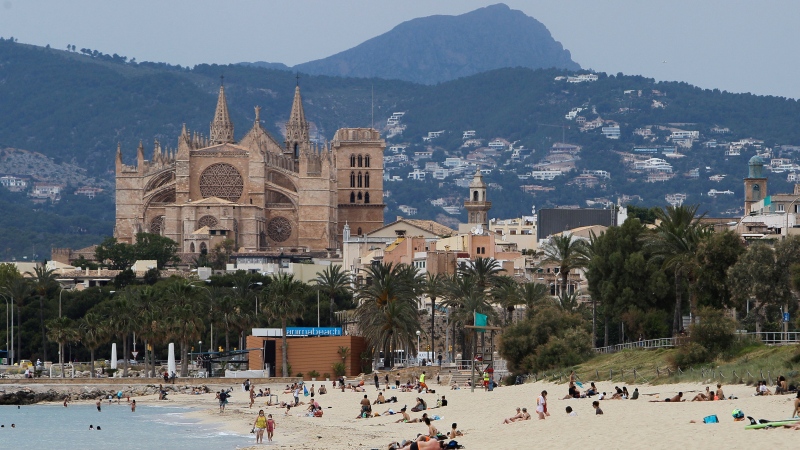 In this May 25, 2020 photo, people sit on the beach in Palma de Mallorca, Spain. (Isaac Buj / Europa Press via AP)