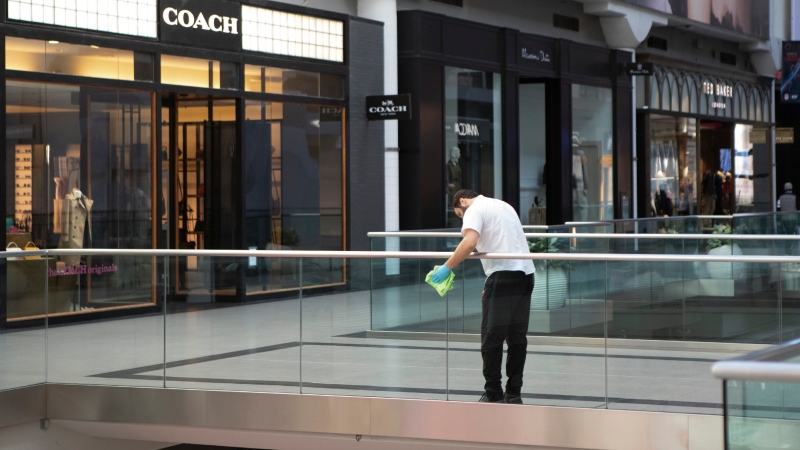A cleaner wipes a glass panel at Toronto's Eaton Centre Shopping mall on Saturday, March 21, 2020. THE CANADIAN PRESS/Chris Young